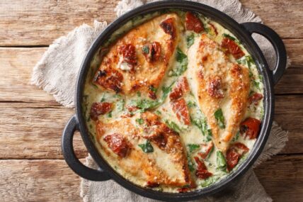 Baked chicken with sun-dried tomatoes and spinach in cheese sauce.