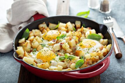 Potato hash with ham and eggs in skillet